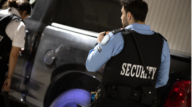 security guard using a flash light to inspect a vehicle