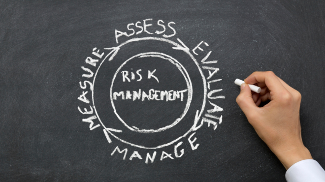 A females hand in a cuff shirt drawing the diagrams of risk management and the stages: Assess, Evaluate, Manage, Measure