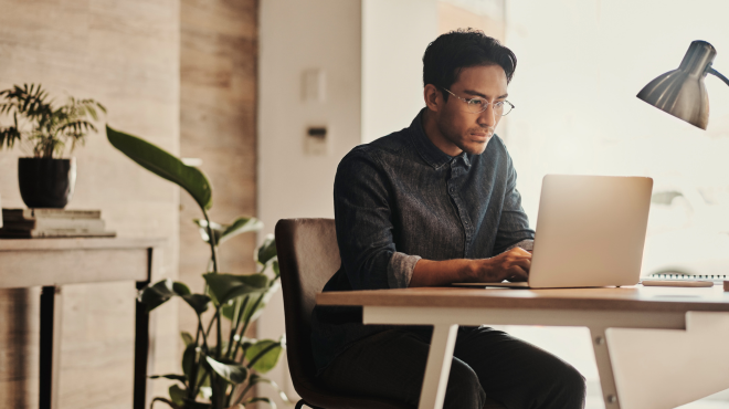 Young asian male filling out application online at a desk.