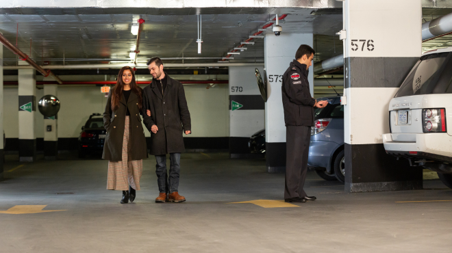 a security guard taking notes on a vehicle inside a parking garage